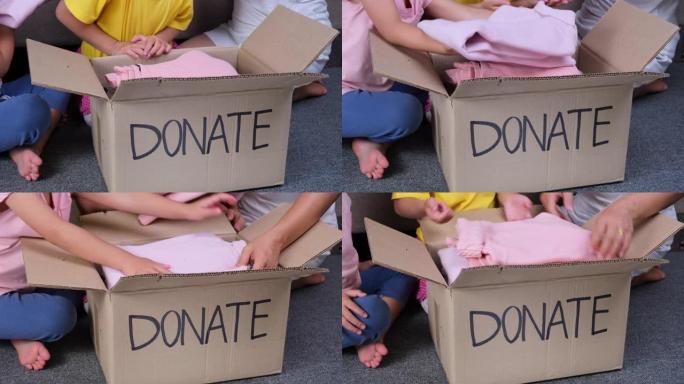两个可爱的姐妹和她的母亲把她的衣服放进家里的捐款箱里，帮助穷人。捐赠理念。