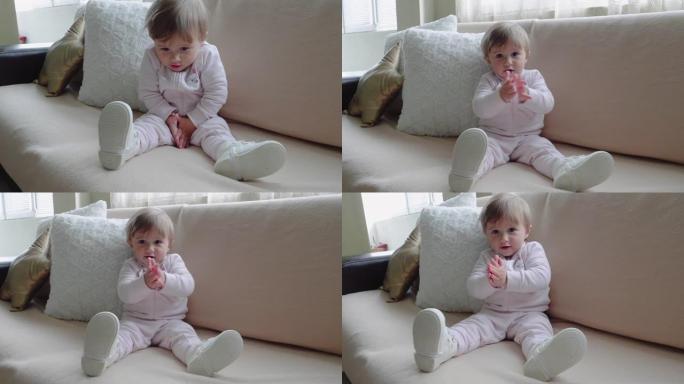 快乐的宝宝坐在家里的沙发上拍手大笑，特写镜头。