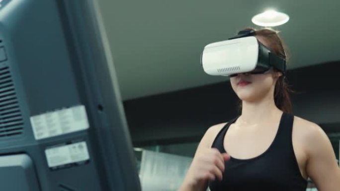 喜欢健身的年轻女子在健身房锻炼时使用虚拟现实进行虚拟跑步