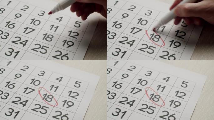 男人的手用红笔在纸质日历上写下第18天。