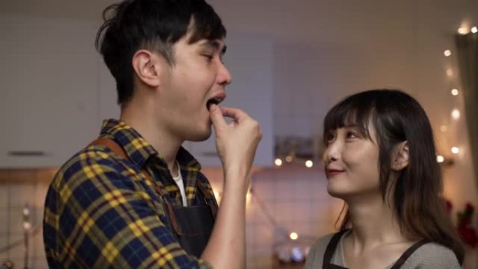 一个充满爱心的亚洲男友在一起准备情人节晚餐时与女友喂食并分享黄瓜片的特写镜头