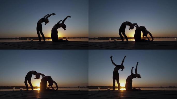 两个做双人瑜伽运动的小女孩的剪影，一起在户外伸展