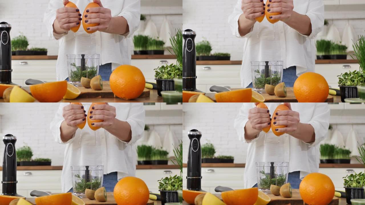 一个女人的手挤压橙汁制作麦汁冰沙的特写镜头。witgrass，健康食品