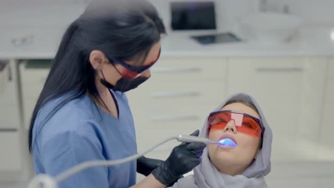 在办公室工作的牙医。年轻女子带着设备跑步。年轻病人的脸特写。戴护目镜的病人和医生。