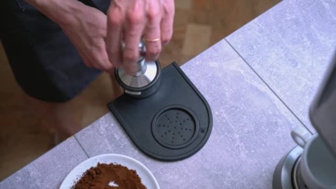 咖啡师使用篡改在portafilter中篡改咖啡。特写鲜咖啡制备流程