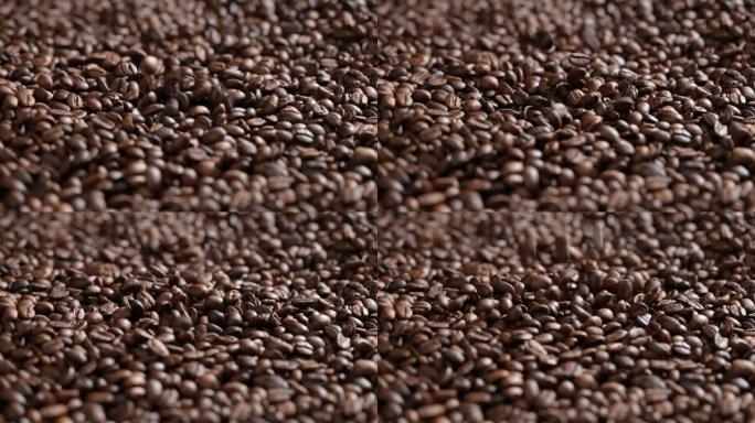烤咖啡豆落入一堆咖啡豆。一大堆新鲜烘焙的浓郁芳香咖啡豆。慢动作。