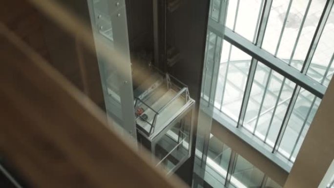 开放式玻璃透明电梯轿厢在建筑物内升起。