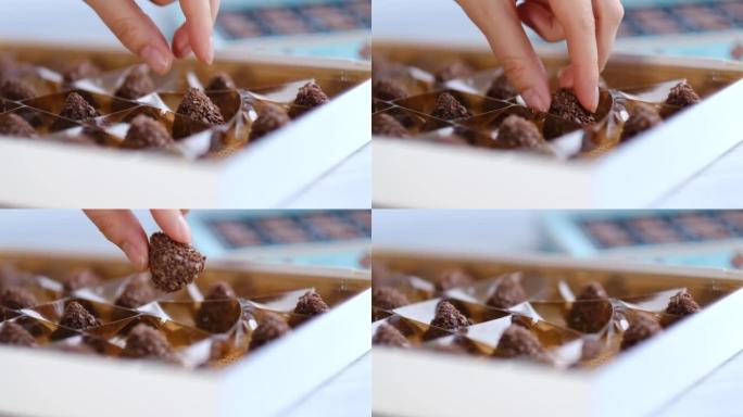 女人从一盒不同的糖果中取出一颗巧克力。特写拍摄素材。慢动作