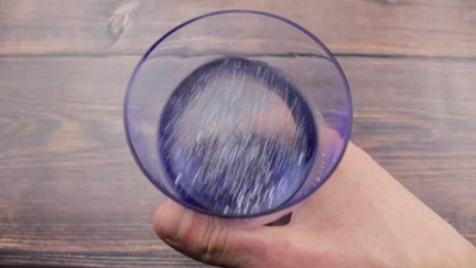 白色粉末在水中的溶解度。玻璃杯里的粉末。