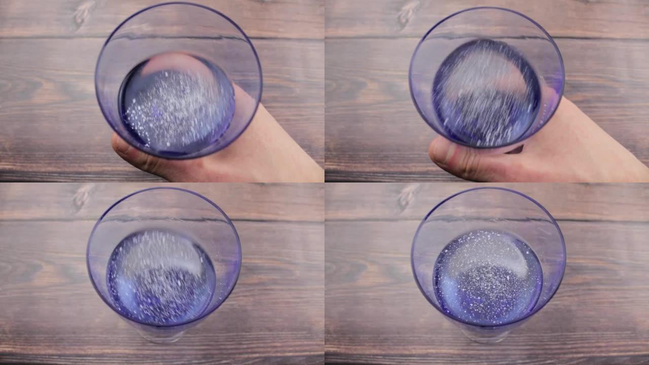 白色粉末在水中的溶解度。玻璃杯里的粉末。