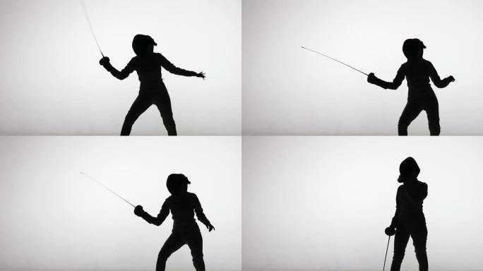 年轻女子剑客用剑投掷攻击打击的剪影。击剑学校的运动训练。女运动员在聚光灯下的白色背景下在黑暗的工作室