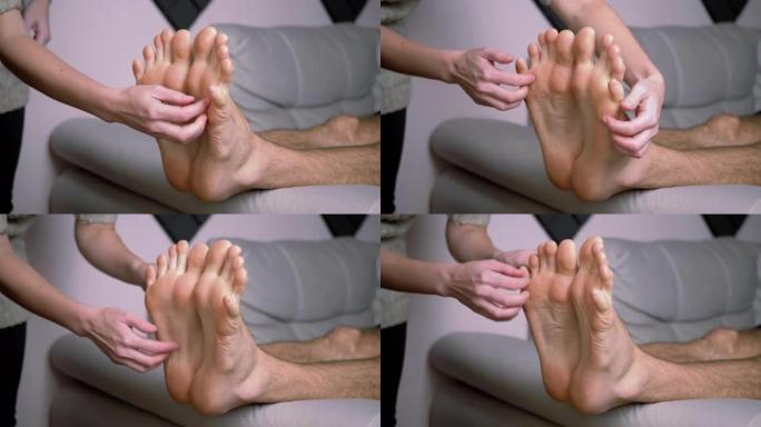 女人的手挠男人的光脚，脚趾，在沙发上伸展。时间流逝