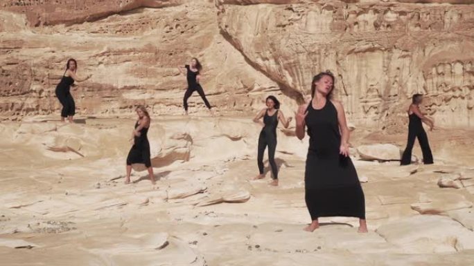 一群身着黑衣的妇女在沙漠峡谷中练习狂喜的舞蹈