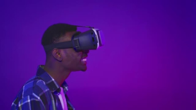 震惊的非洲家伙戴着VR眼镜向一边看，紫色背景