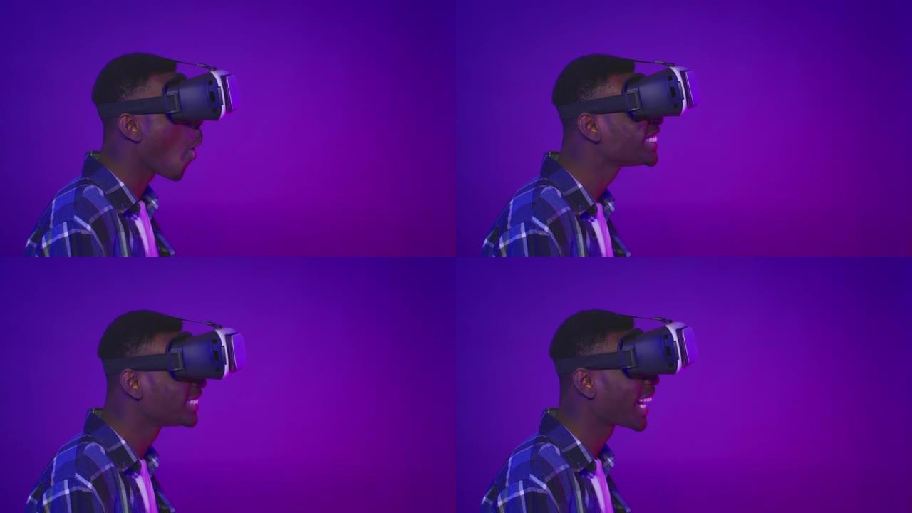 震惊的非洲家伙戴着VR眼镜向一边看，紫色背景