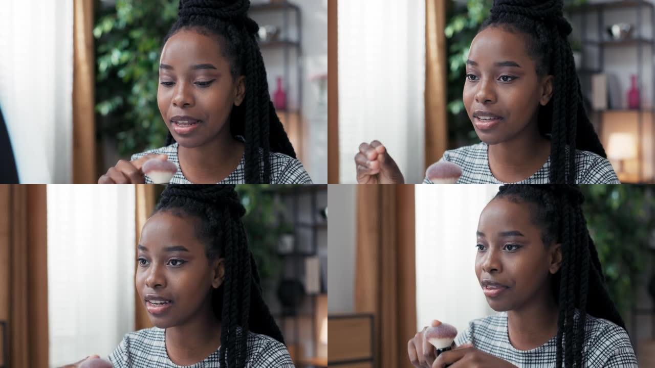 化妆师在非裔美国血统的黑皮肤女人脸上的环灯后面的特写镜头中，与她提供美容建议的粉丝交谈，描述了她使用