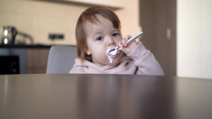 孩子用勺子吃酸奶，餐桌上的儿童早餐，特写镜头，toodler自己吃，1年儿童食品