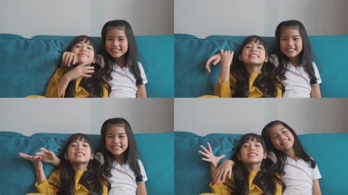 肖像快乐两个亚洲女孩是沙发上微笑的朋友。