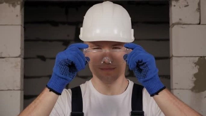一名年轻的男性建筑工人戴上保护性建筑眼镜。