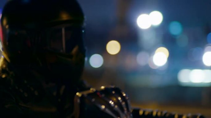 靠近头盔骑摩托车的摩托车手，在城市有夜灯