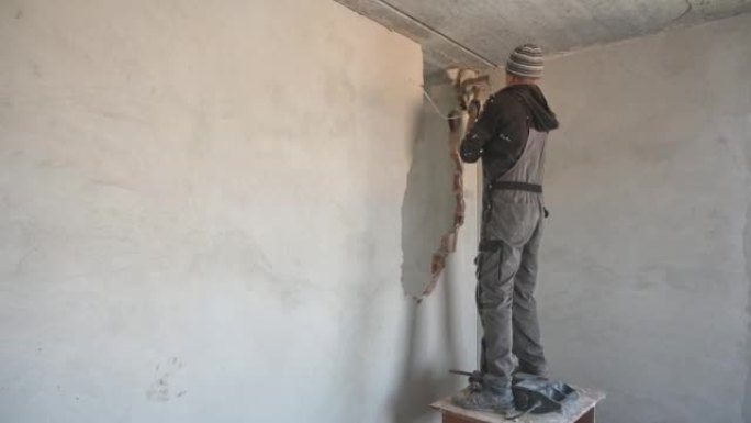 男工在公寓里用大锤破墙。