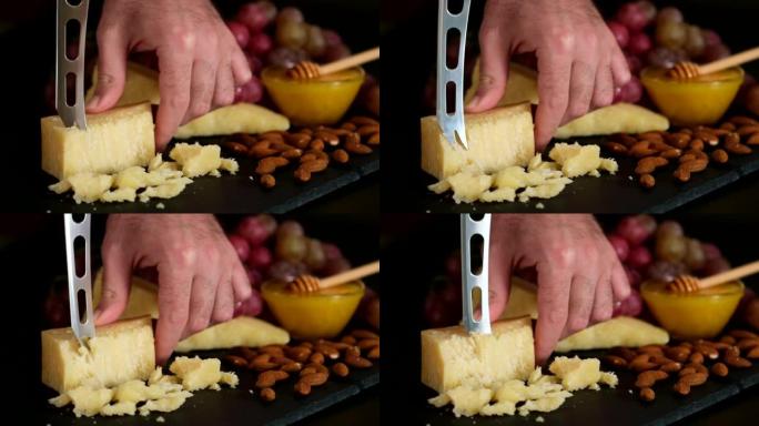 奶酪盘的制备: 帕尔马干酪、葡萄、蜂蜜、坚果。切菜板上有刀的硬帕尔马干酪块。美食开胃菜或休闲食品。各