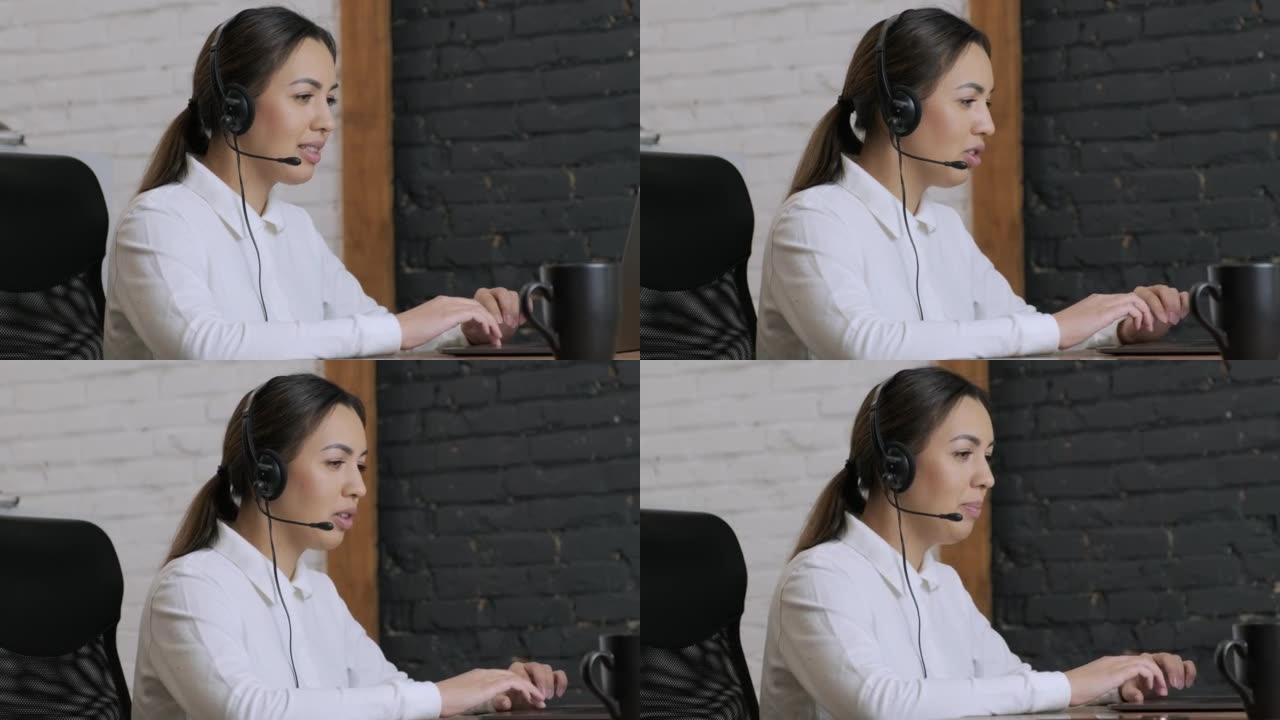 微笑的女性呼叫中心接线员，客户支持代理戴着耳机咨询客户在笔记本电脑上的在线打字，在互联网上聊天，帮助