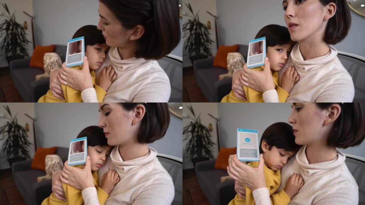 母亲在网上咨询中使用设备看男孩的耳朵。