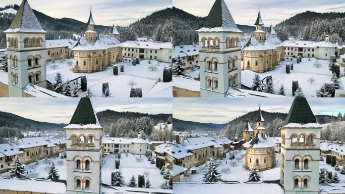 罗马尼亚冬季普特纳修道院的空中无人机视图。内院有步行的游客，光秃秃的树木，雪，周围的山丘