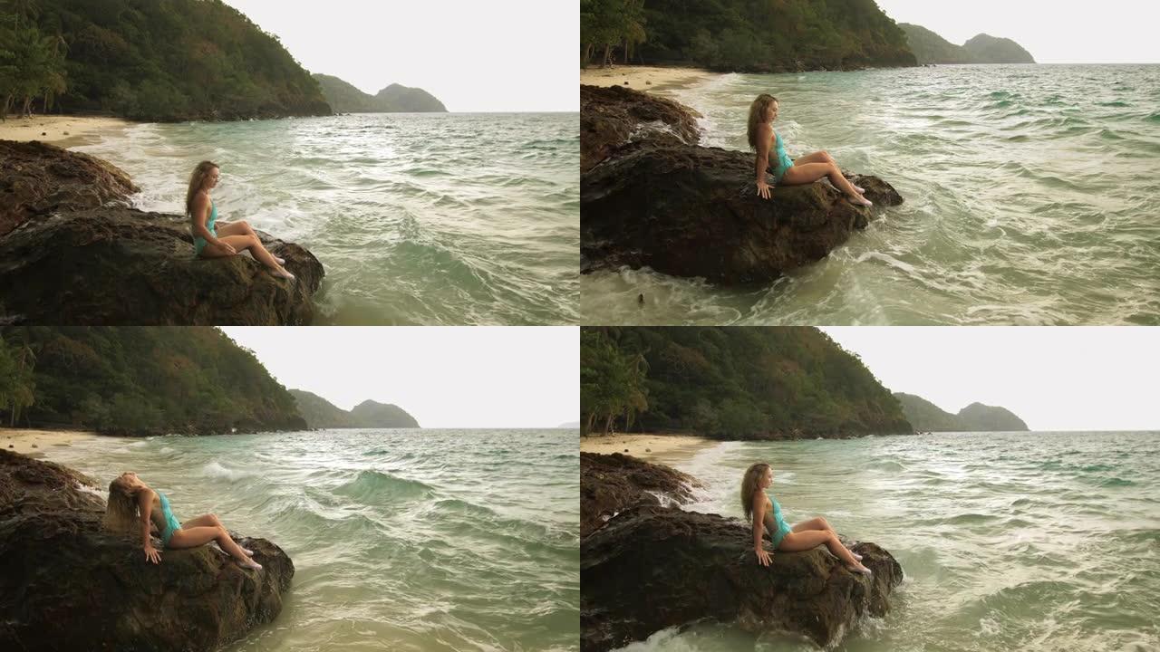 女人冷静放松休息在海礁石上，暴风雨多云的海洋。穿着泳衣的女人束腰外衣。概念休息热带户外旅游