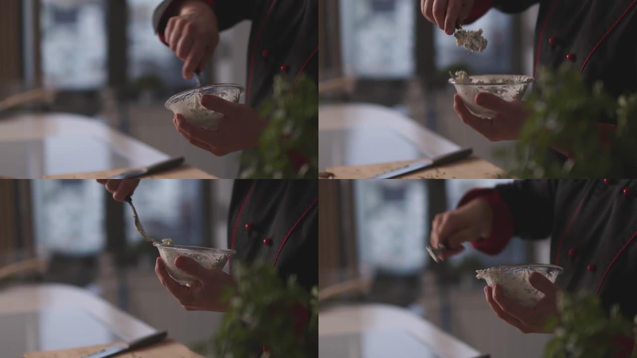 厨师在碗中混合新鲜细香葱和奶油芝士的手持照片