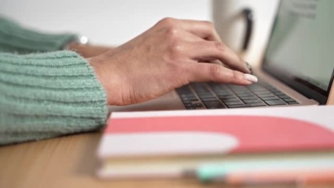 在现代笔记本电脑上打字的女性手的特写做笔记。女人在键盘上写作和工作