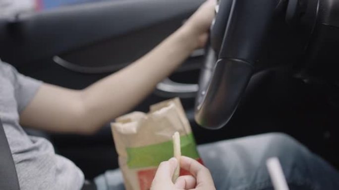开车时吃炸薯条的人。