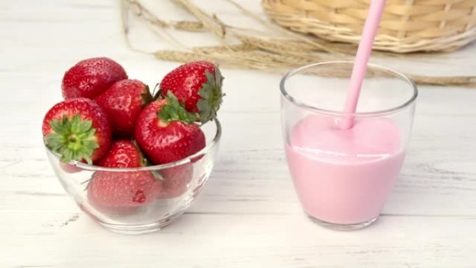 将奶油酸奶杯和时令成熟的草莓一起倒入木制乡村桌子上的碗中