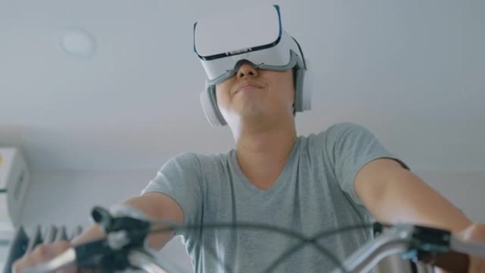 一名亚洲男子在新型冠状病毒肺炎禁闭期间用VR护目镜在家骑自行车。