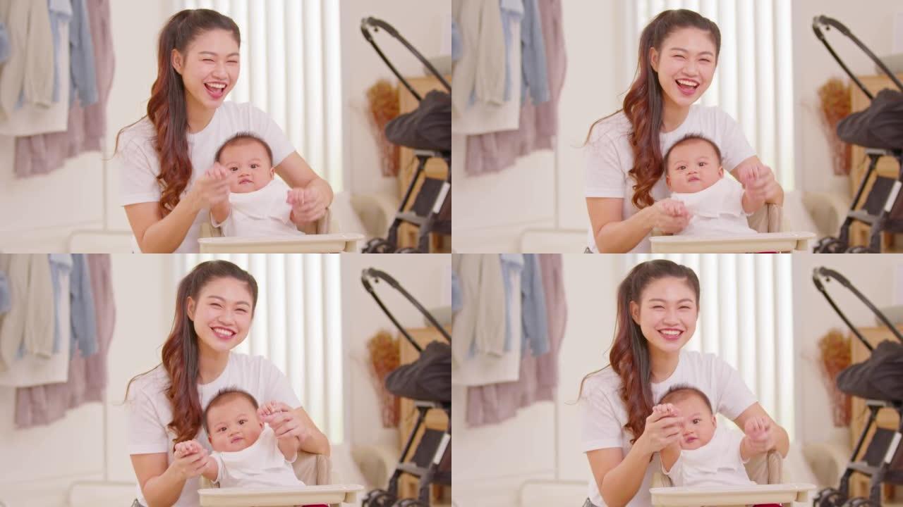 快乐的亚洲妈妈和她的新生宝宝玩耍，一起在家看着相机。可爱的男婴微笑着在温暖的地方和妈妈一起笑，放松和