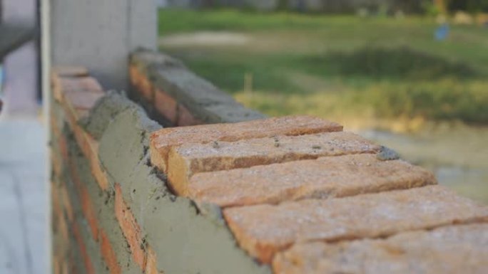 建筑商的手将砖块放在家里的墙壁砌筑中