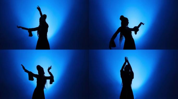 长发在蓝色灯光和烟雾中跳舞的女人的剪影