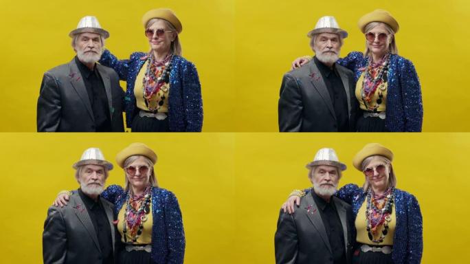 年老的男人和女人。黄色背景上时尚的老年妇女。她戴着帽子和眼镜。戴着帽子胡须的时尚男人。