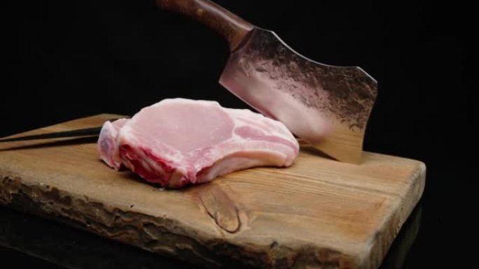 烤木板上的黑色背景上的生猪肉排特写。农场肉店，屠宰牛