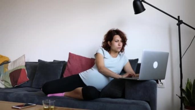 一位专注的孕妇在舒适的公寓里度过怀孕的日子，在家工作