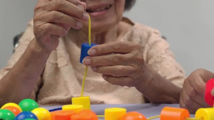 护理人员和老年妇女玩串珠游戏预防痴呆症