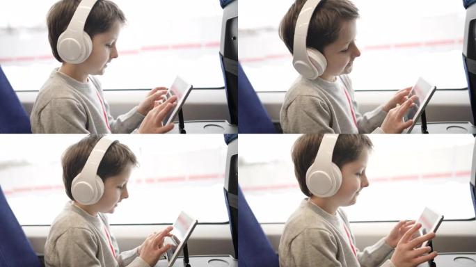 坐在火车上的孩子，坐在窗边的平板电脑上看卡通或玩游戏的孩子。