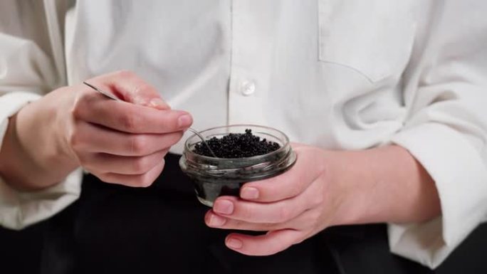 黑色鱼子酱特写。厨师拿着玻璃弓和白鲸鲟鱼鱼子。生海鲜。豪华美味食品。美味可口的鱼产品。俄罗斯美食。节