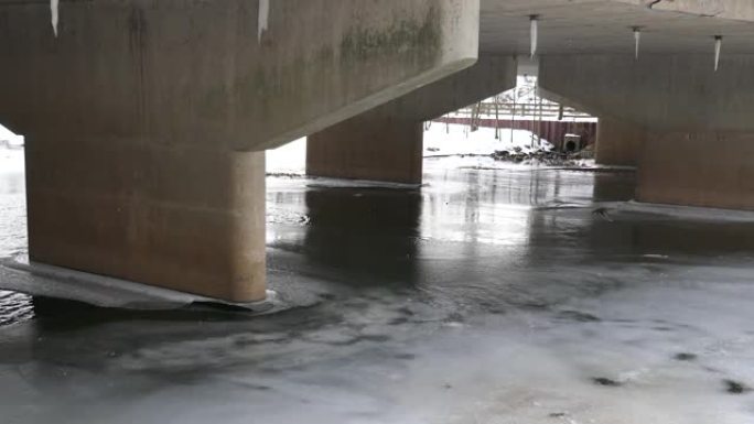 鸭子在冰冻的河上的混凝土桥下迅速飞行