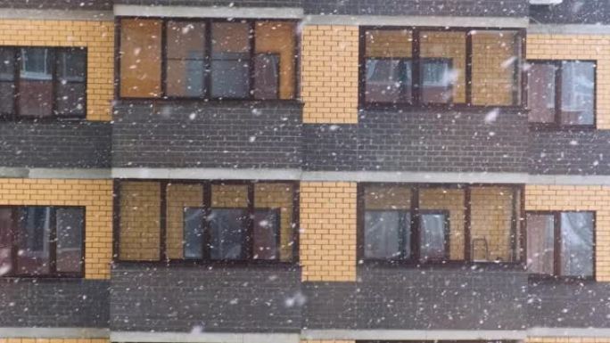 寒冷下雪的冬天，城市一栋公寓楼的窗户前降下了大雪。雪花飘落得很快