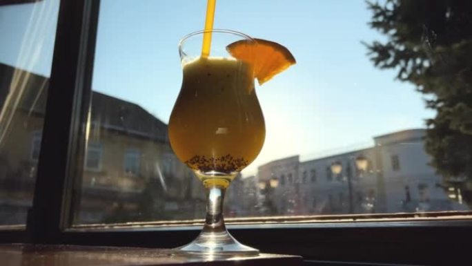 猕猴桃汁和橙子饮料在窗户和明亮的阳光下的背景下，玻璃玻璃上有一块橙子