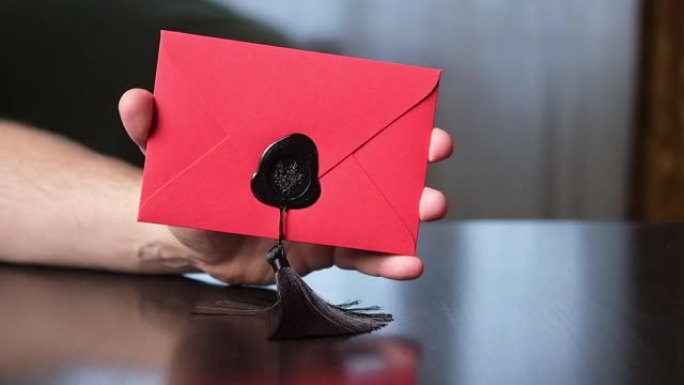 一个用密封蜡密封在男人手里的红色信封。通信，情书概念。