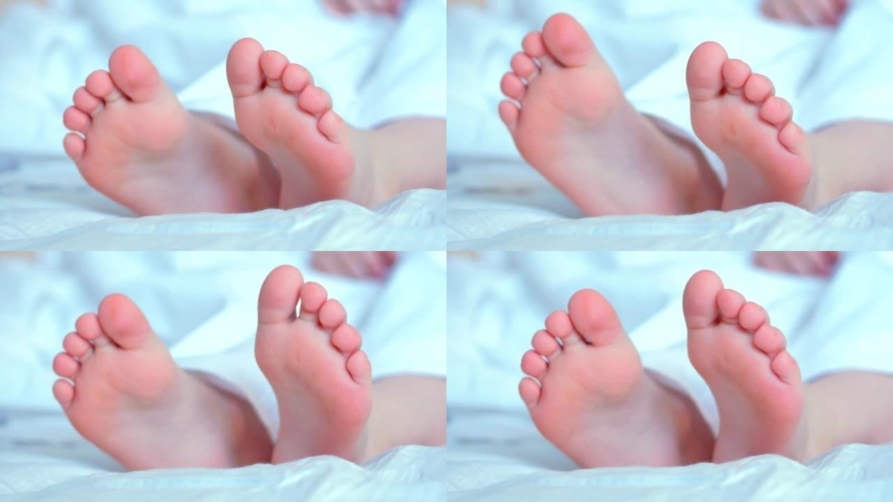 白色移动的孩子的赤脚。手指靠近。懒惰的早晨，觉醒
