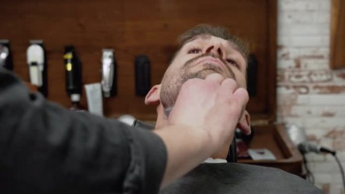 理发师用锋利的剃刀刮胡子的男性。高质量4k镜头